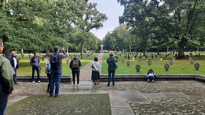 Eine kleine Gruppe Menschen fotografiert eine Kriegsgräberstätte