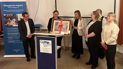 Fünf Menschen stehen im Halbkreis hinter Rednerpult
