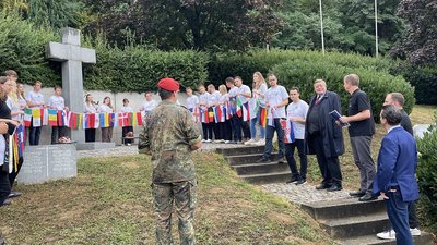 Workcamp-Gruppe hält an einem Hochkreuz das Band, an dem Flaggen aufgereiht sind